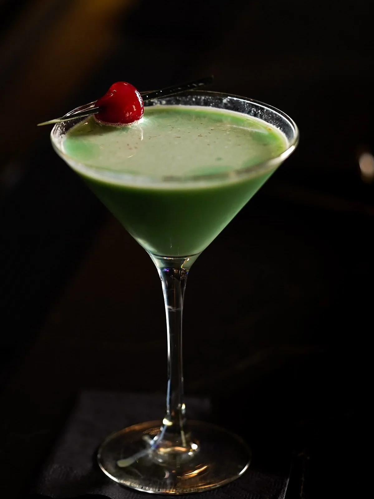 A cocktail served up, garnished with a cherry