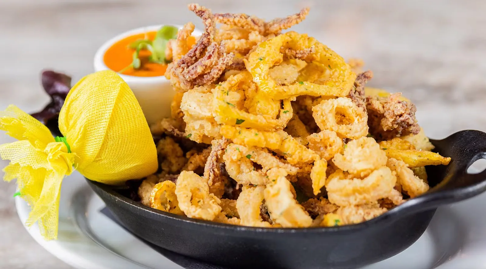 Crispy calamari served in a cast iron pan with cherry peppers and marinara