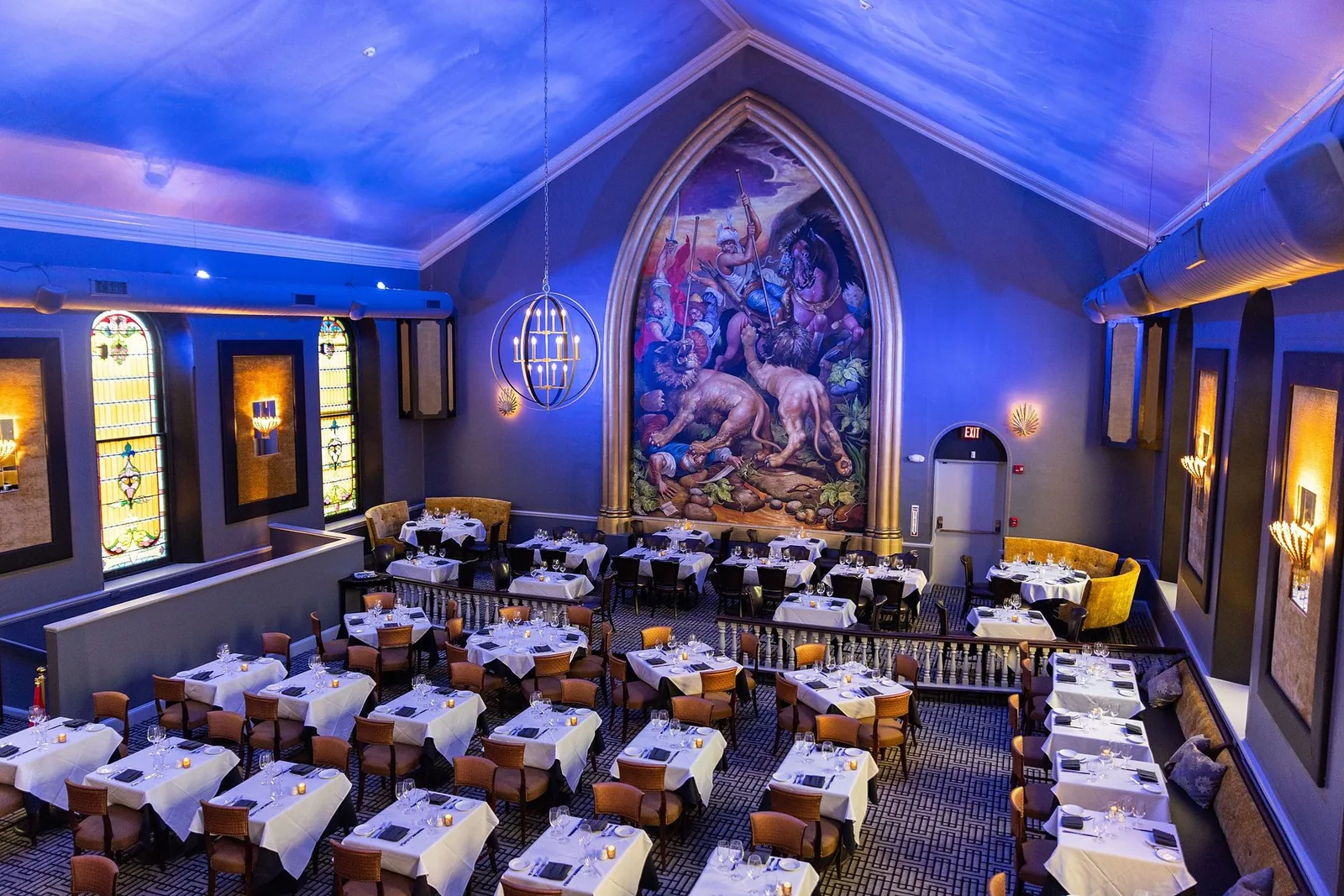 The main dining room at OldeStone Steakhouse, set beneath the vaulted ceiling and mural of the former church sanctuary