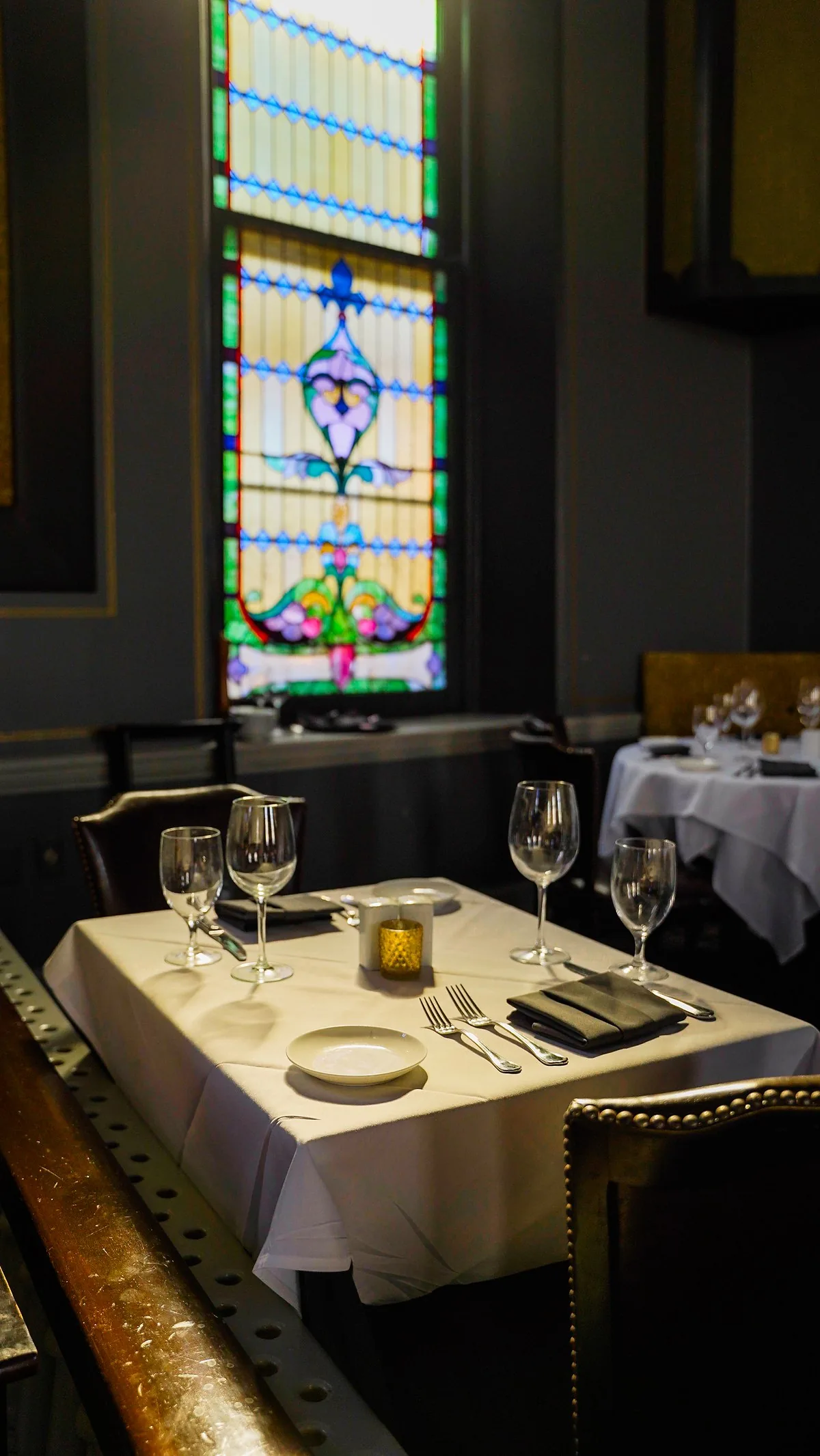 A table set for two beside one of the original stained glass windows